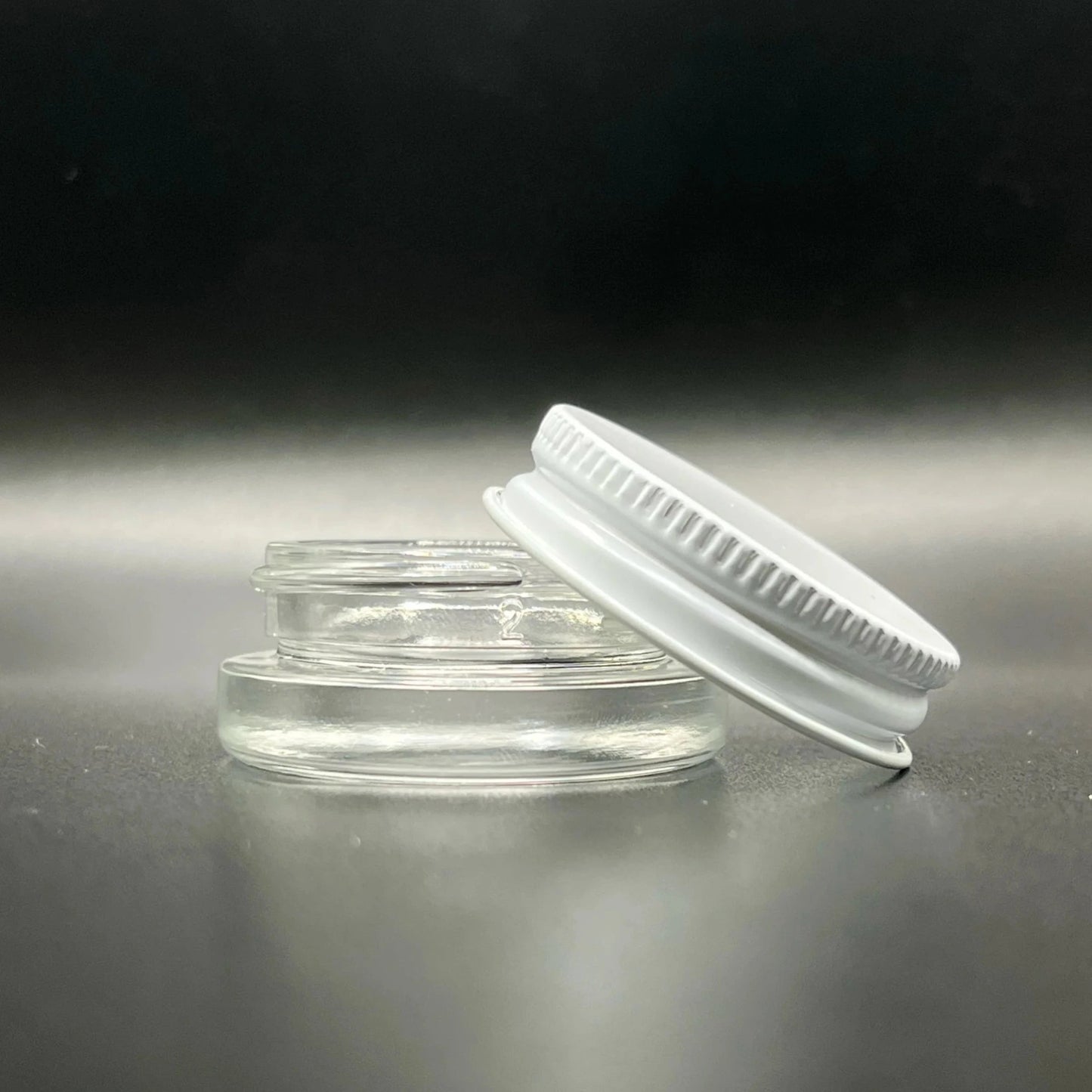 Clear plastic container with a white lid on a reflective surface