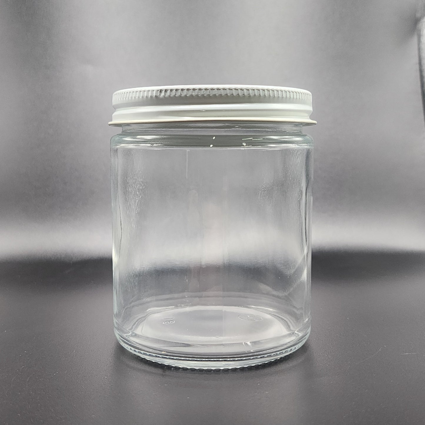Clear glass jar with a metal lid on a gray background