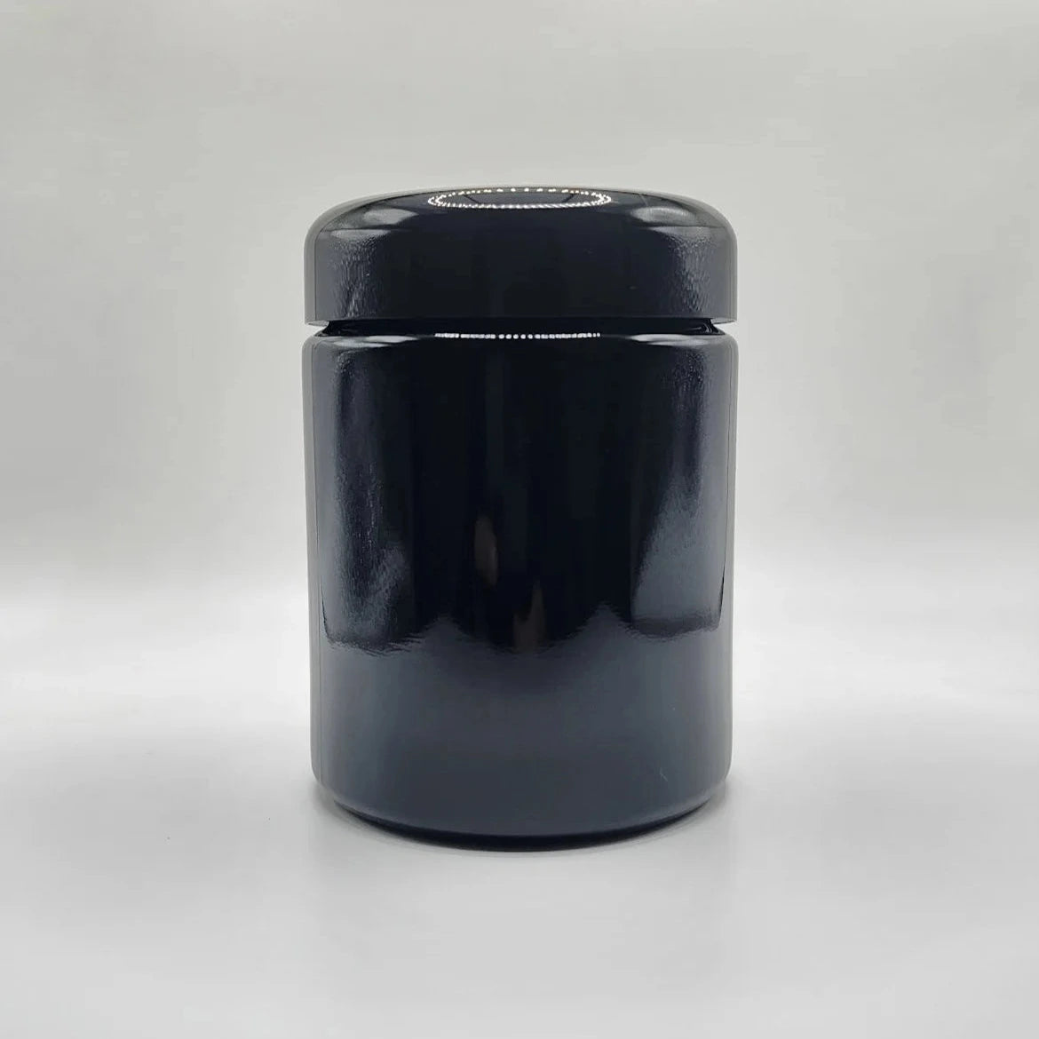 Black glass jar with a lid on a white background