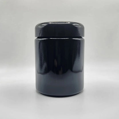 Black glass jar with a lid on a white background