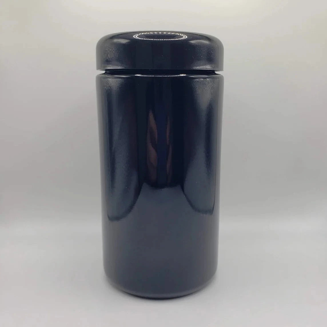 Black glass jar with a lid on a white background