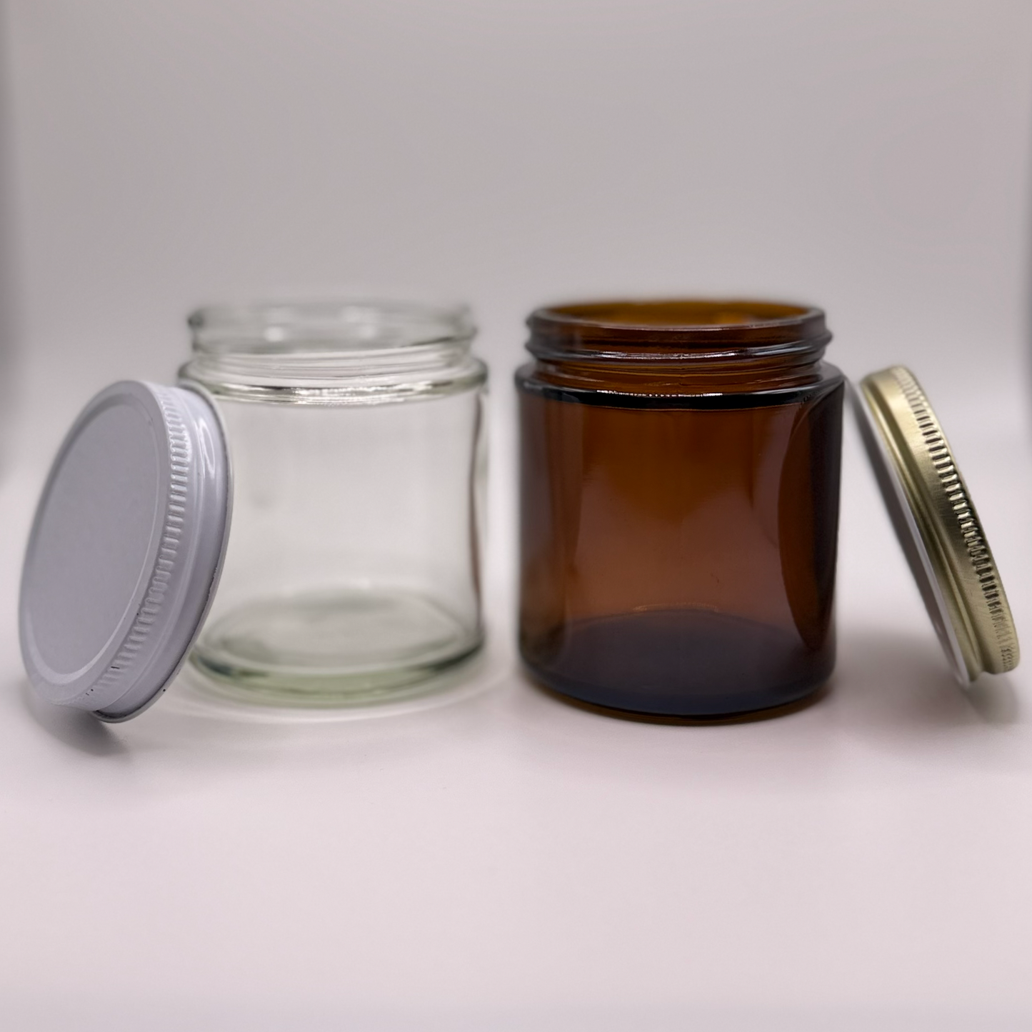 Two different colored glass jars with different colored lids on a white background