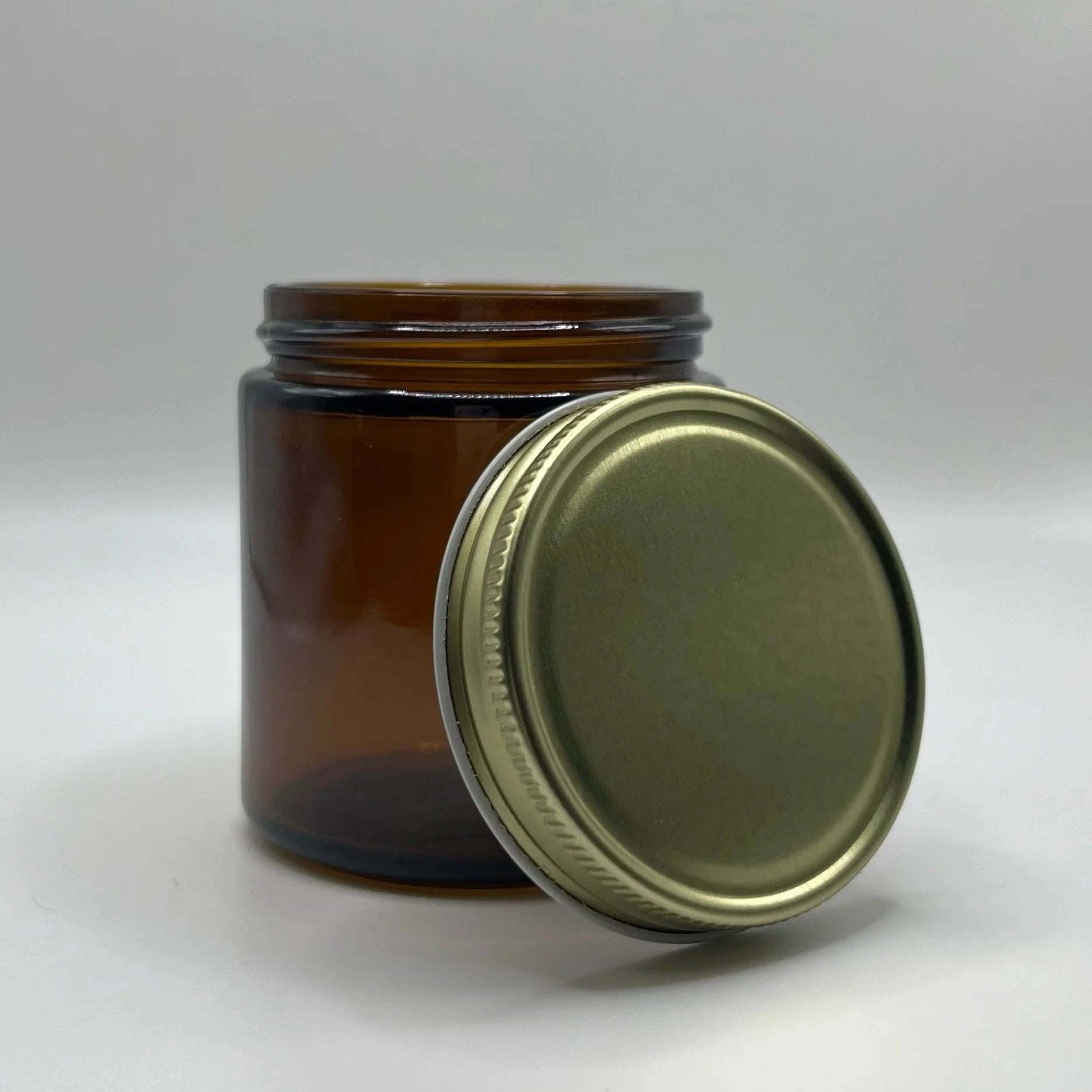Amber glass jar with a gold metal lid on a white background
