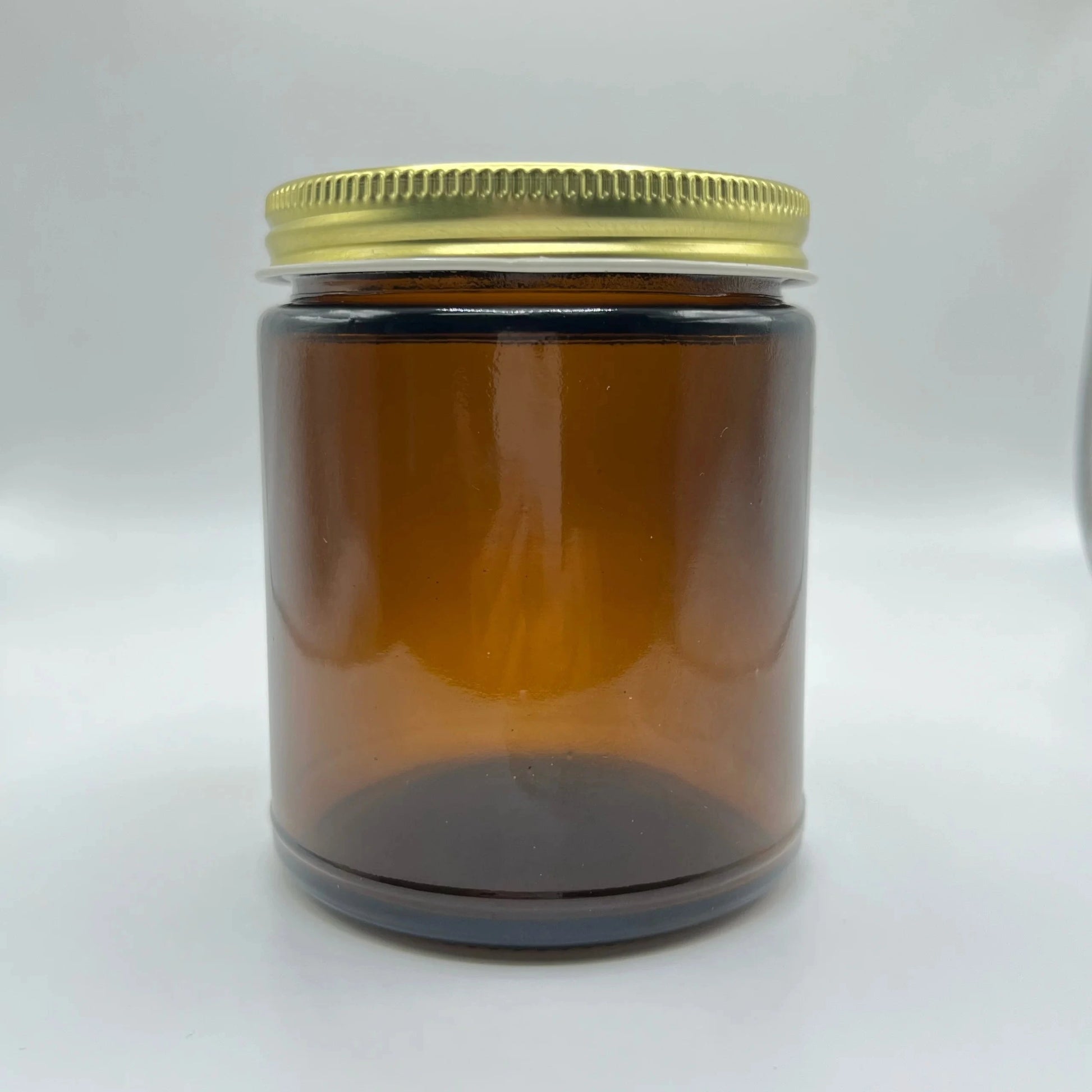 Amber glass jar with a gold lid on a white background