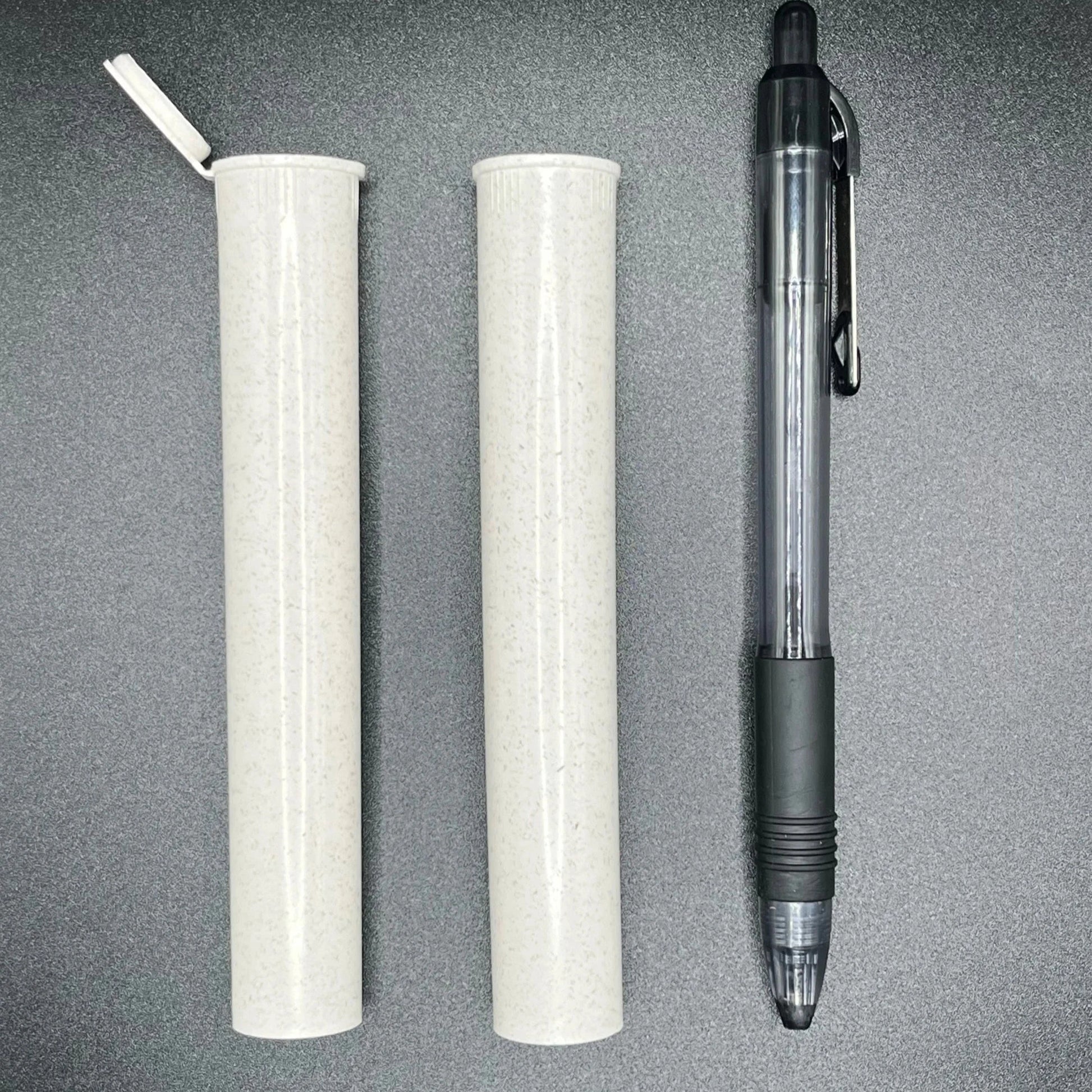 Two cylindrical white tubes and a black pen on a gray surface