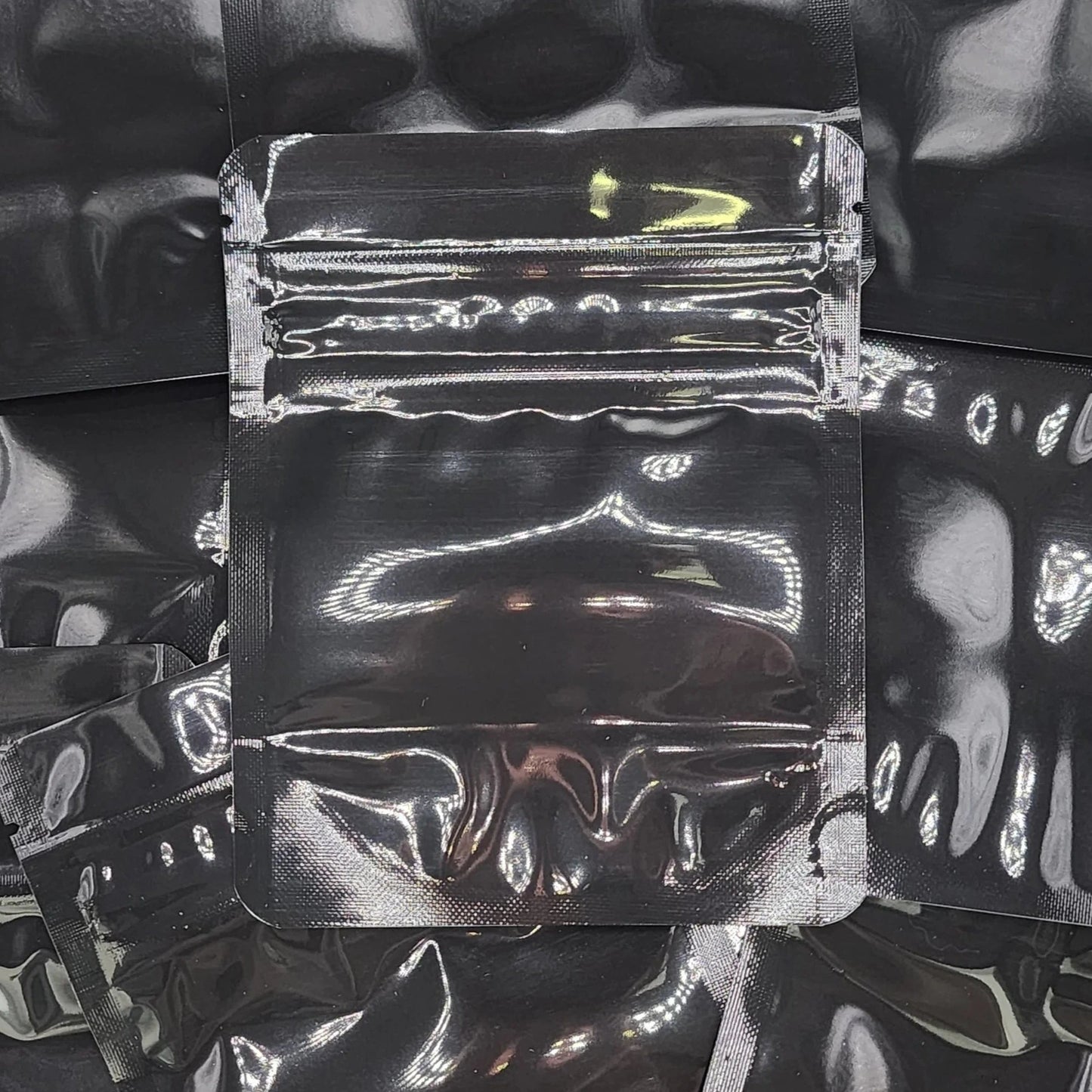 Gloss black 4x5 CR mylar bag on top of other black bags