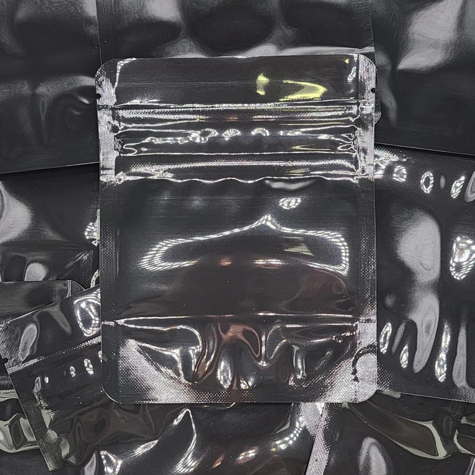 Gloss black 4x5 CR mylar bag on top of other black bags