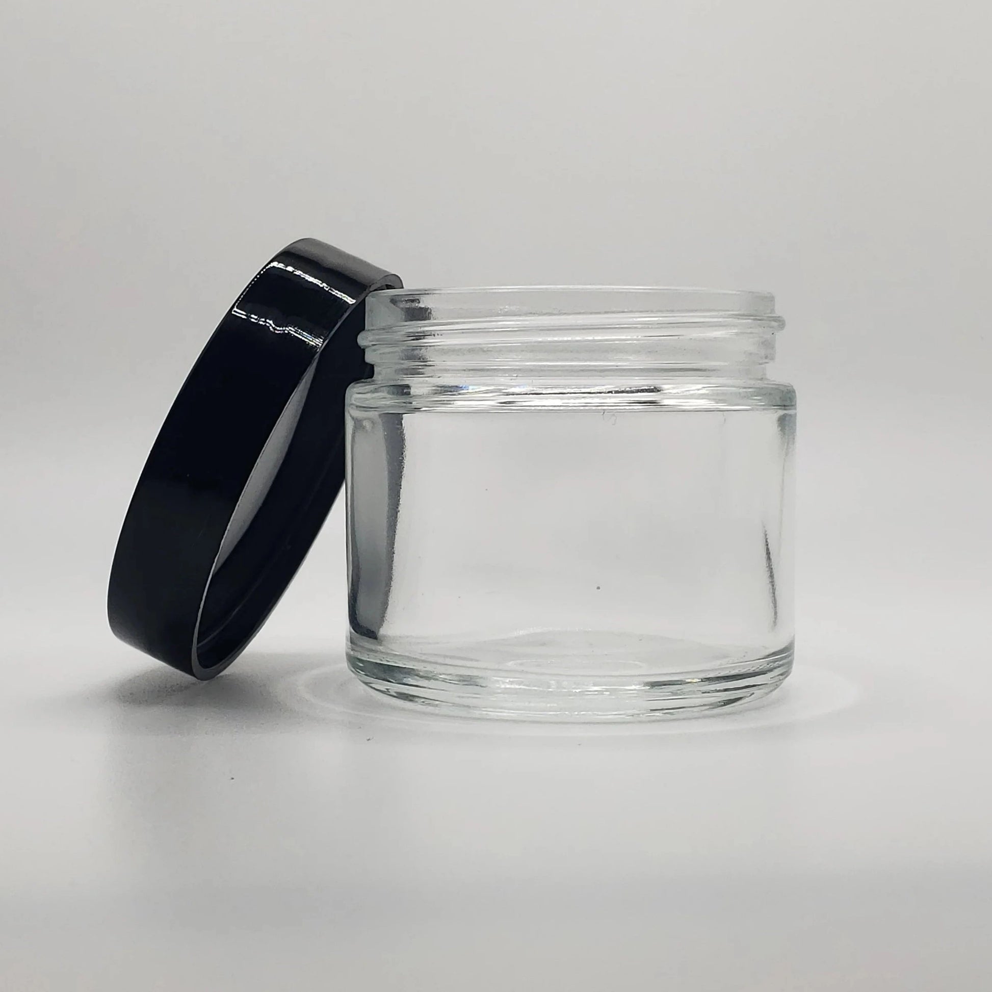 Clear glass jar with a black lid on a light gray background