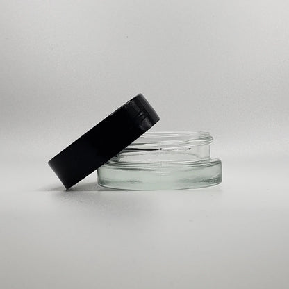 Clear glass jar with a black lid on a light gray background