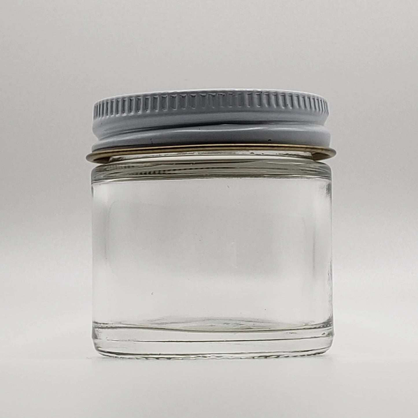 Clear glass jar with a gray lid on a white background