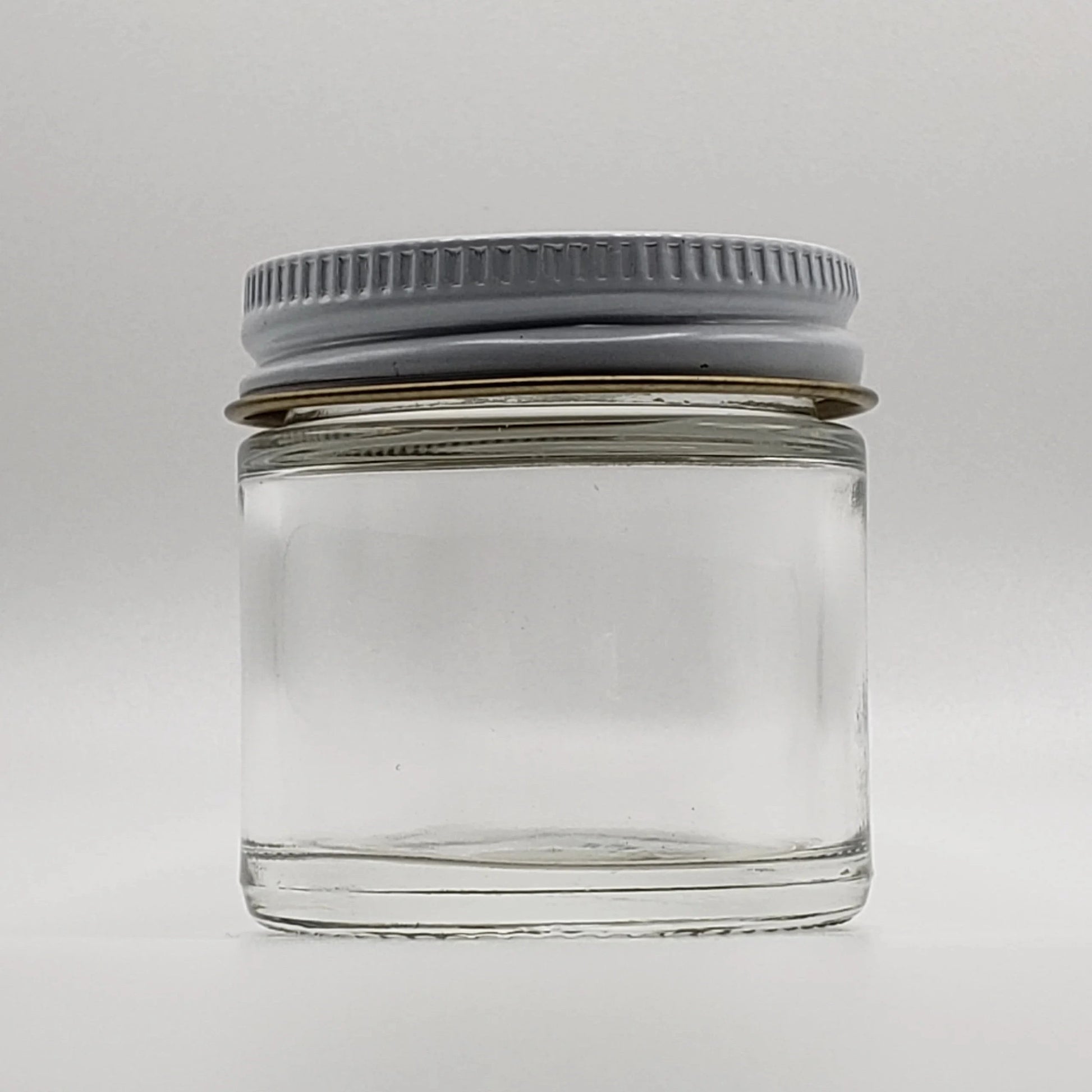 Clear glass jar with a gray lid on a white background