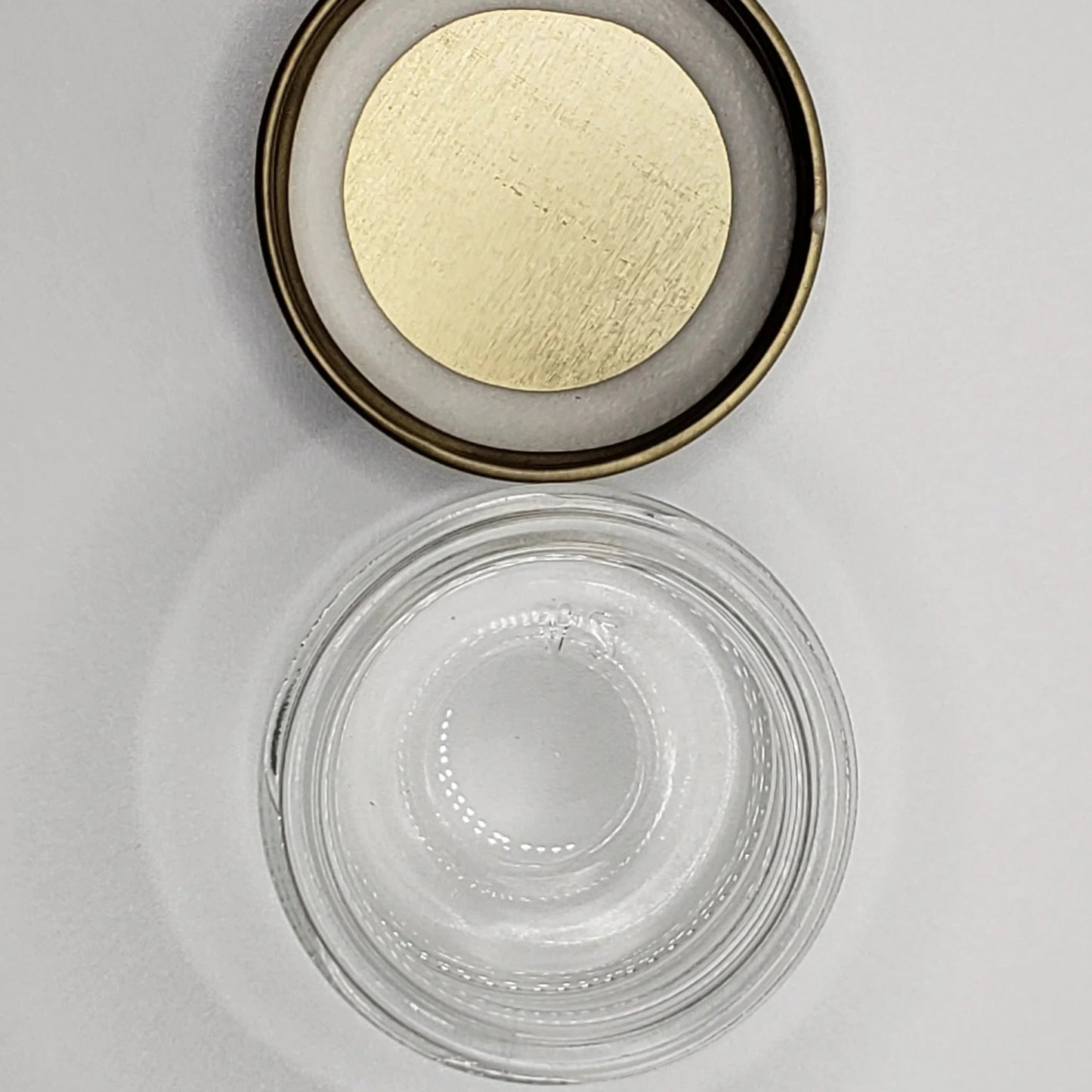 Small glass jar with a gold lid on a light gray background