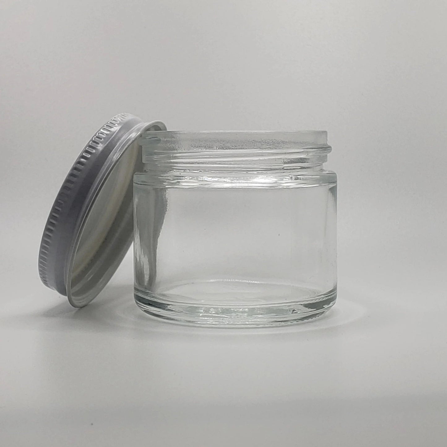 Clear glass jar with a metal lid on a light gray background