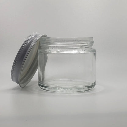 Clear glass jar with a metal lid on a light gray background