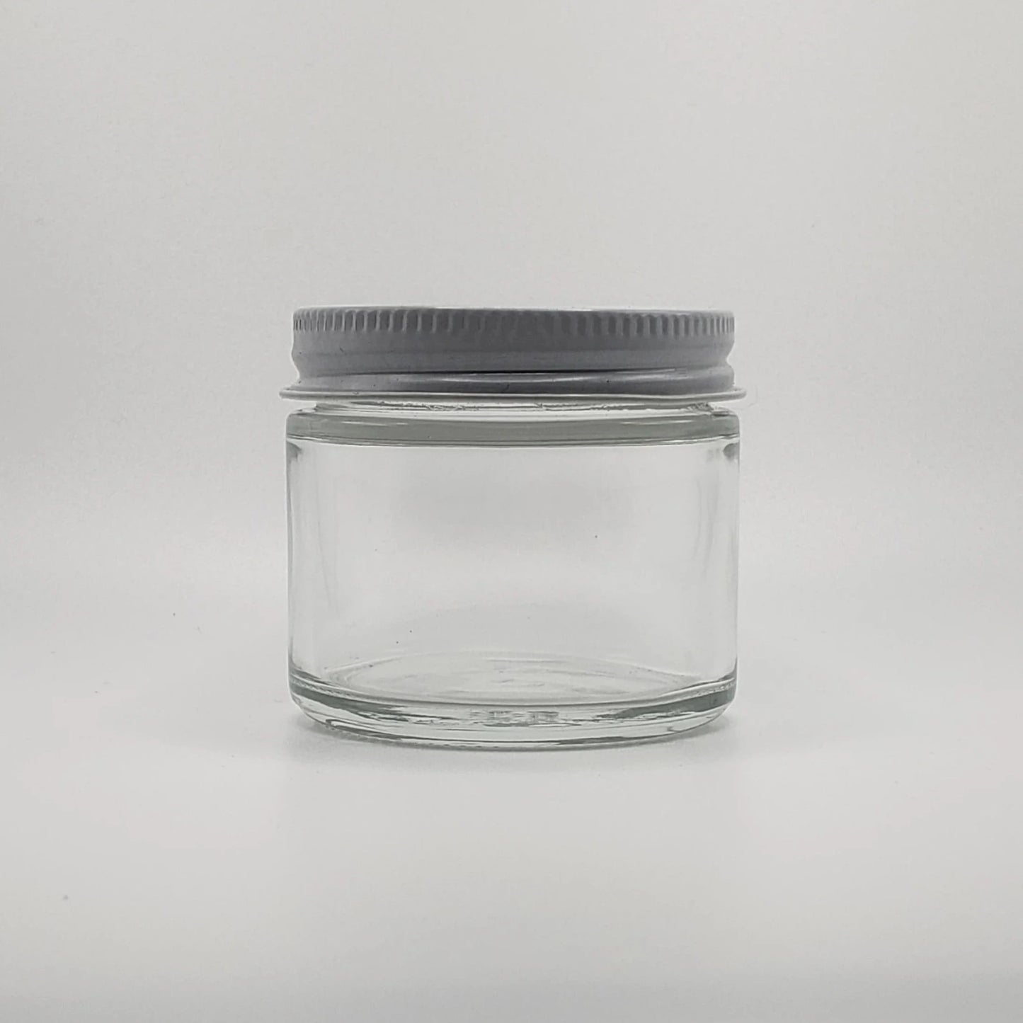 Clear glass jar with a gray lid on a light gray background