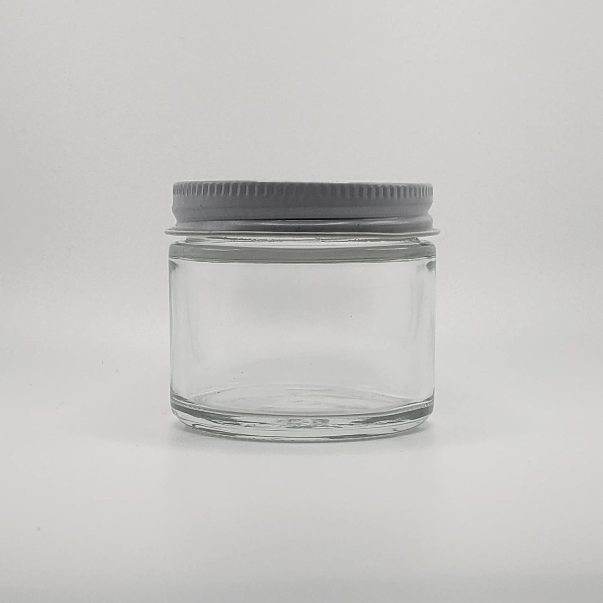 Clear glass jar with a gray lid on a light gray background