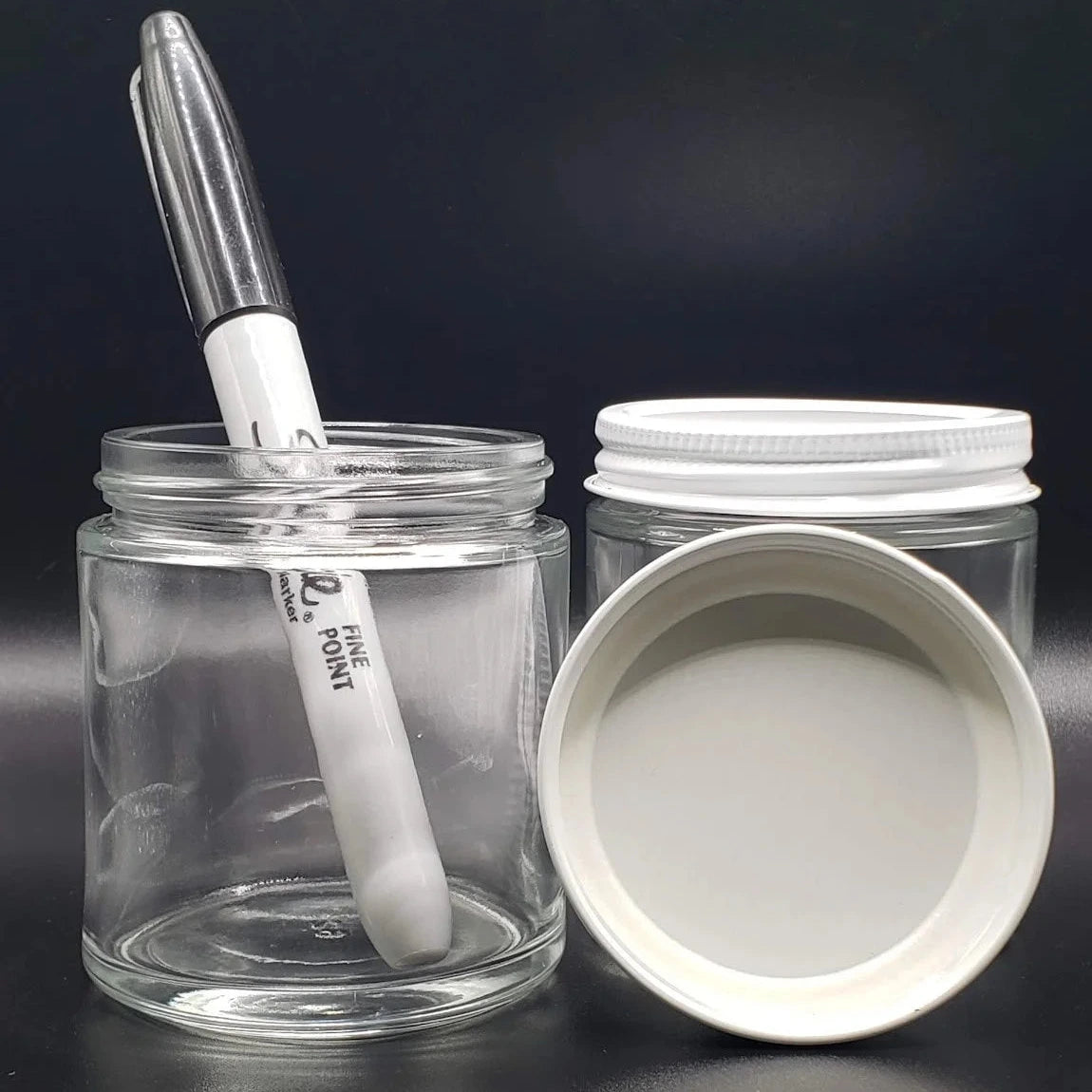 Clear glass jar with a white lid and pen on a black background
