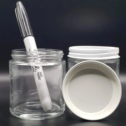 Clear glass jar with a white lid and pen on a black background