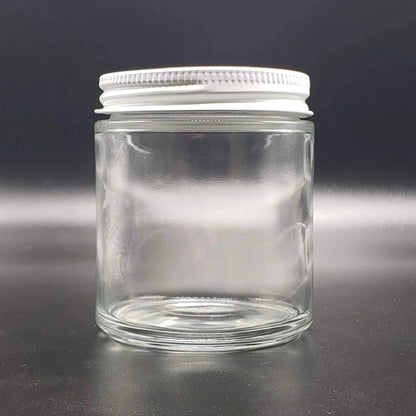 Clear glass jar with a white lid on a black background