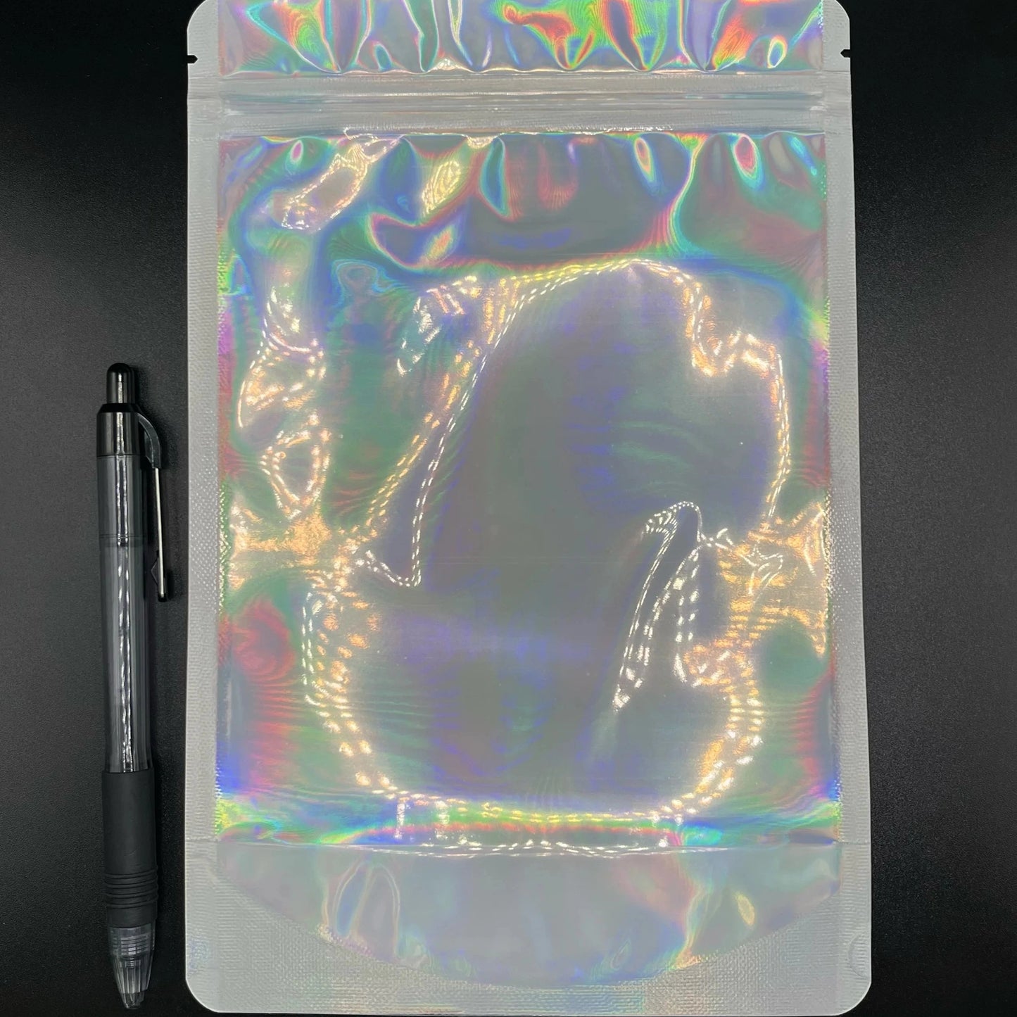 6x9 Laser Black/Clear mylar bag next to a pen on a black background