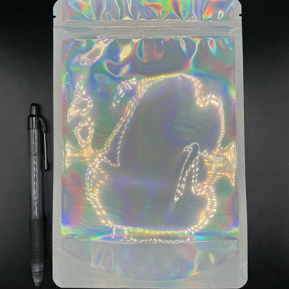 6x9 Laser Black/Clear mylar bag next to a pen on a black background