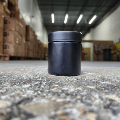 Black cylindrical object attached to a textured wall with blurred indoor background