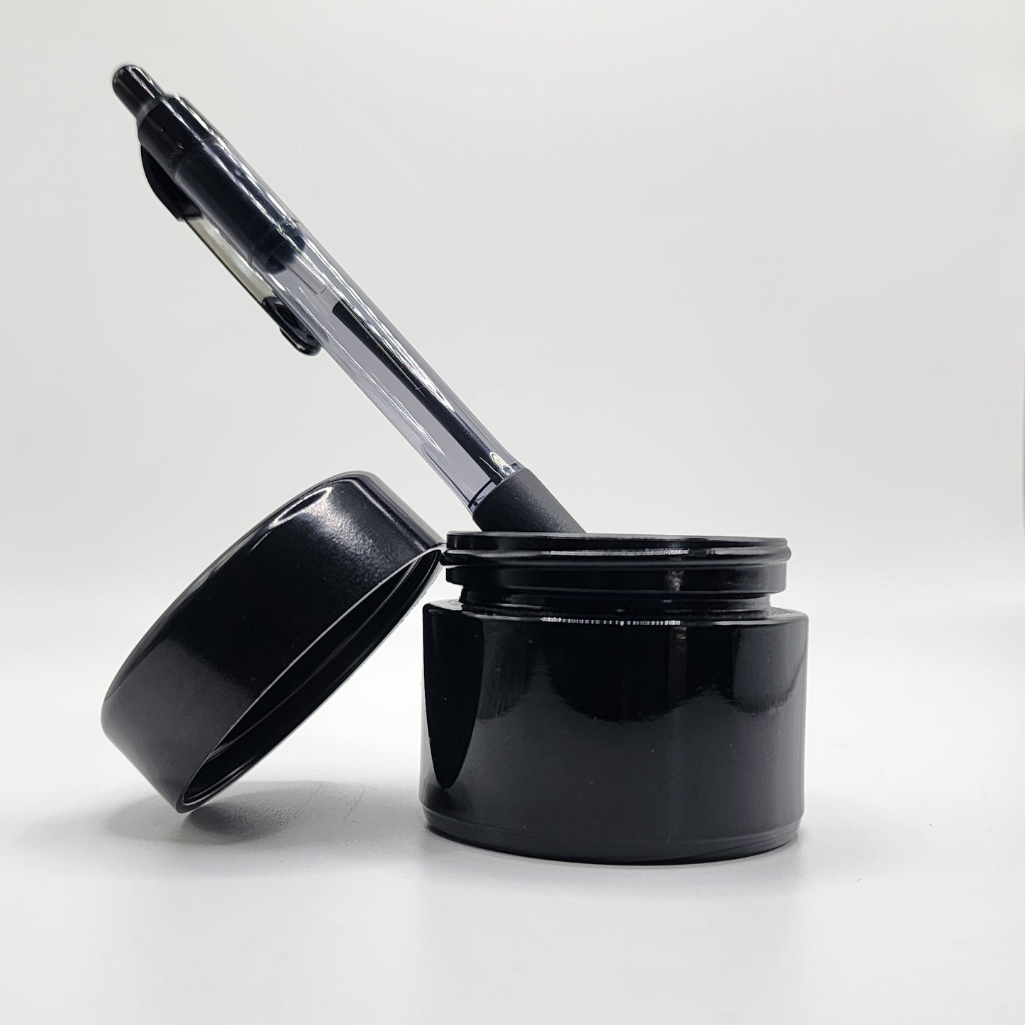 Black pen and black glass jar on a white background