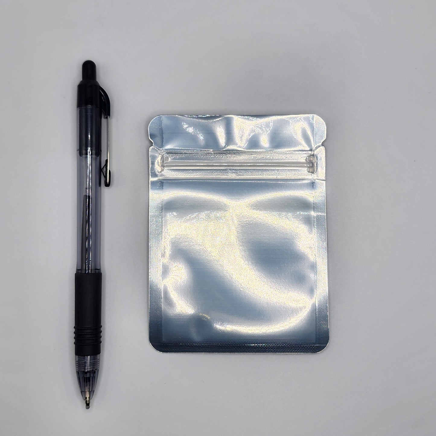 Silver 3x4 mylar bag with a pen on a white background