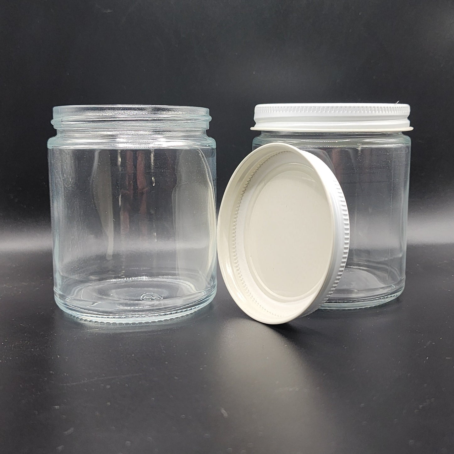 Clear glass jar with white lid on a reflective black surface