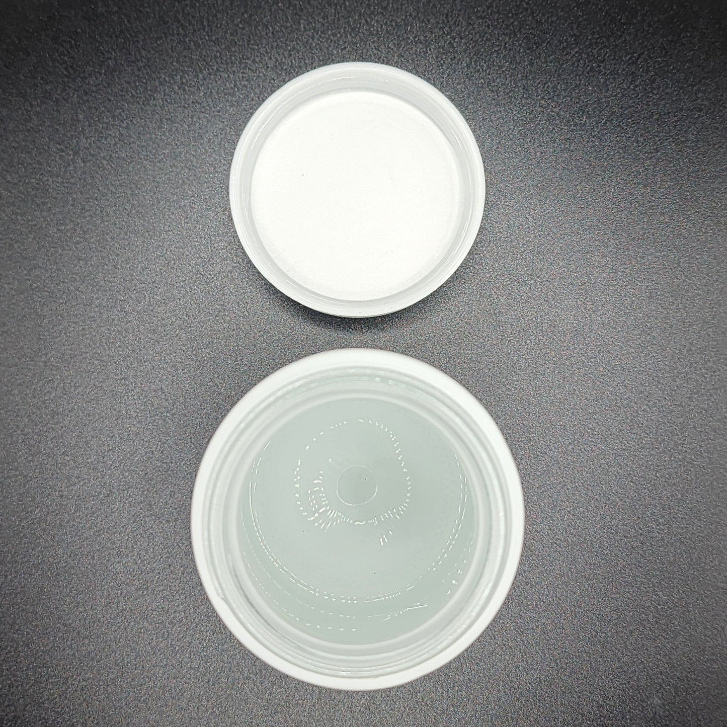 Two white plastic containers on a dark gray surface