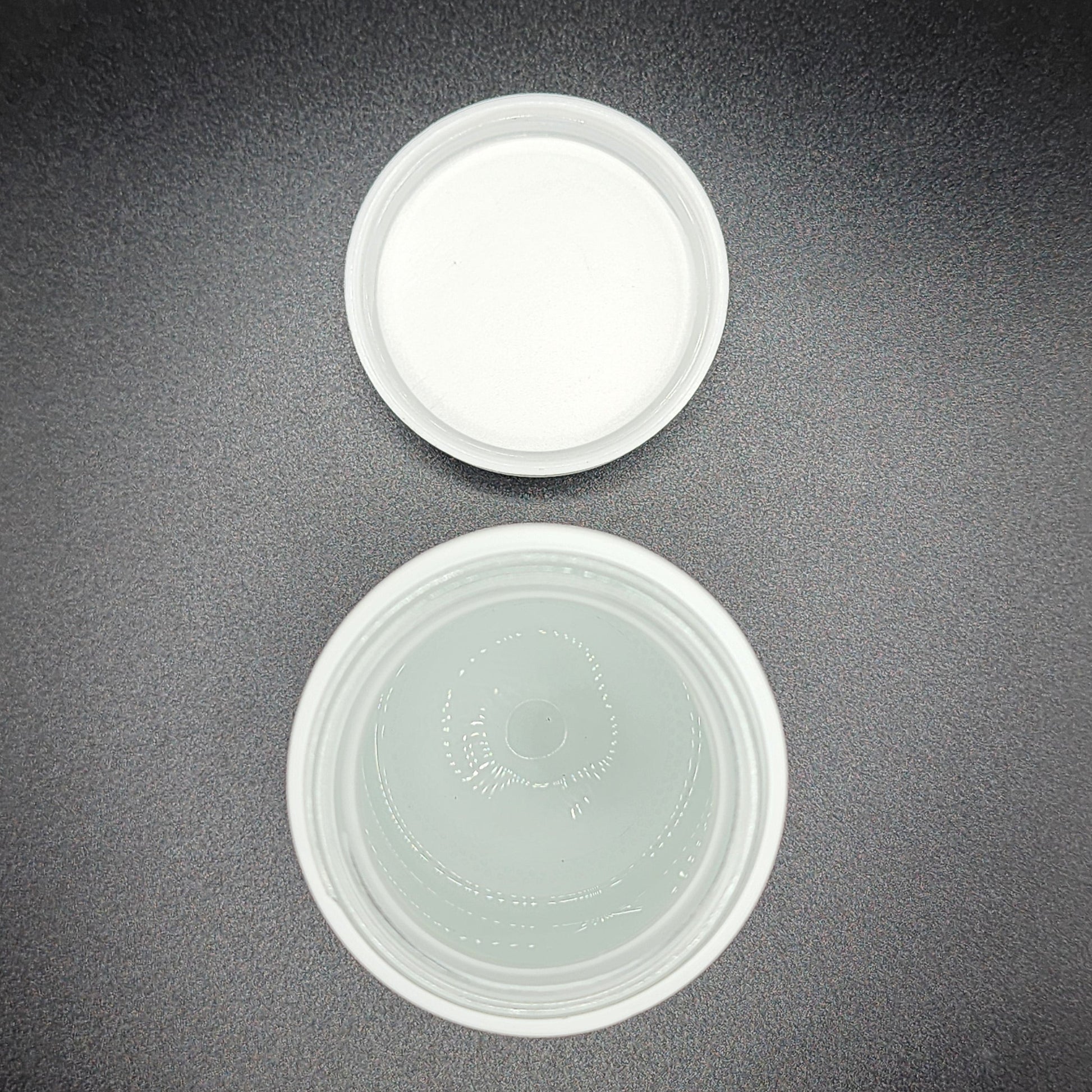 Two white plastic containers on a dark gray surface