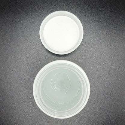 Two white plastic containers on a dark gray surface