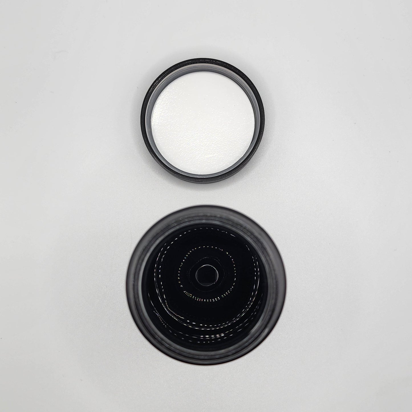 Two black camera lens caps on a light gray background