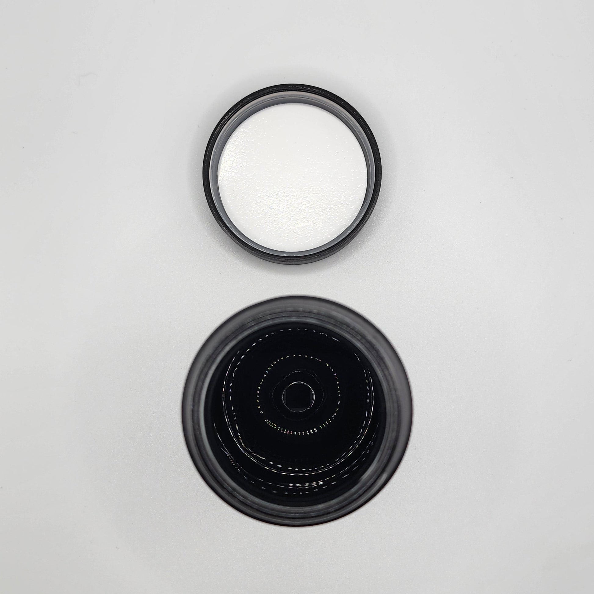 Two black camera lens caps on a light gray background