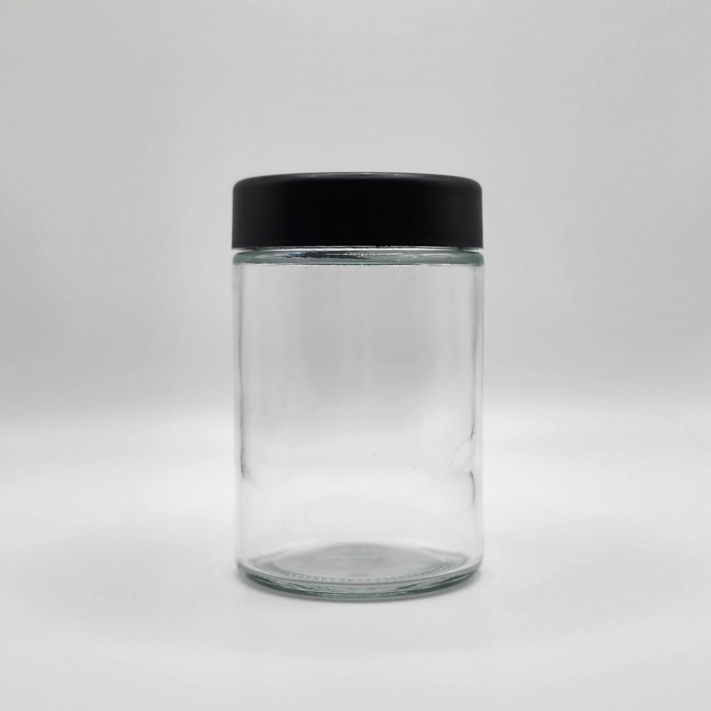Clear glass jar with a black lid on a white background