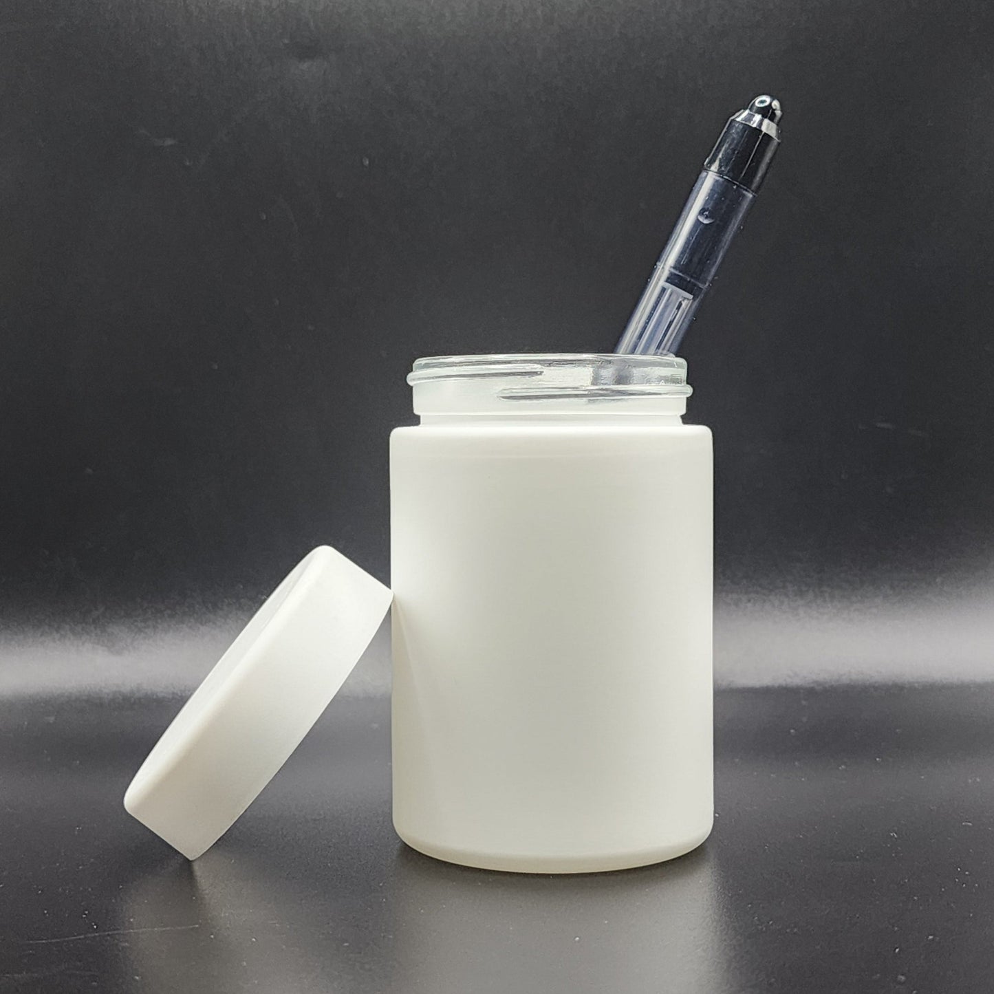 White jar with a pen inside on a black background
