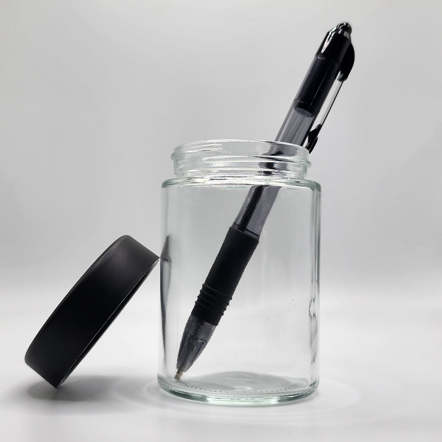Clear glass jar with a black pen inside on a white background