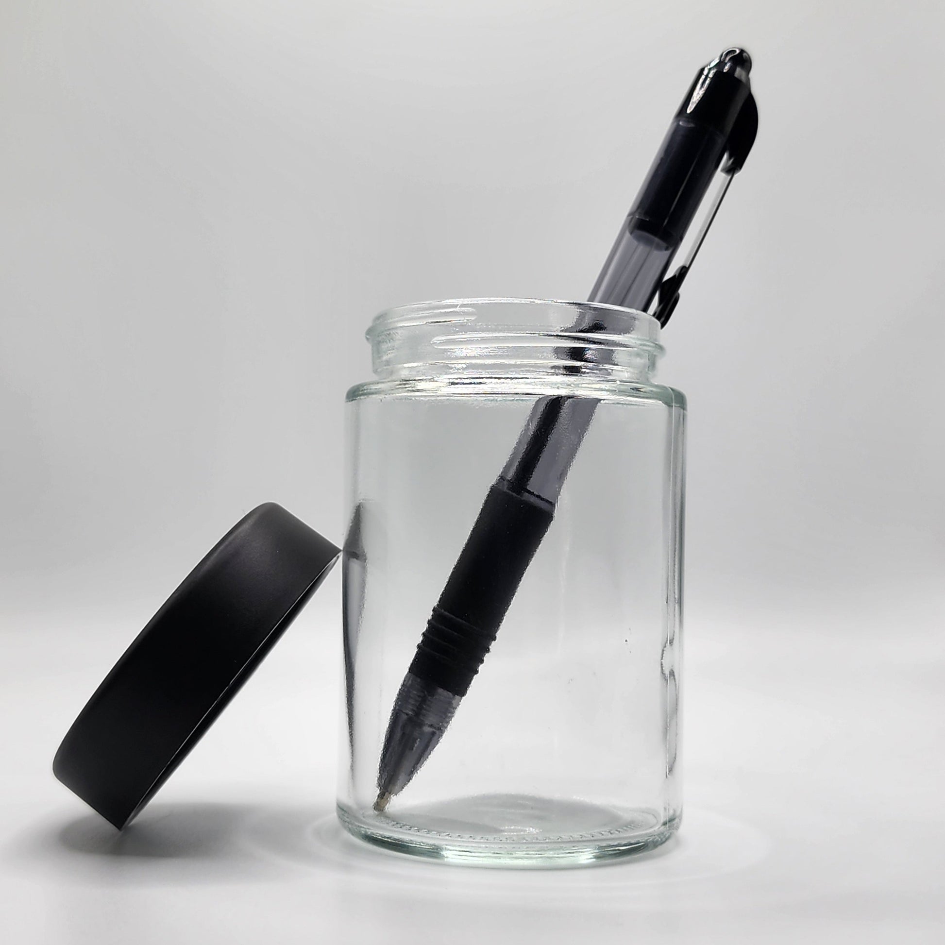 Clear glass jar with a black pen inside on a white background