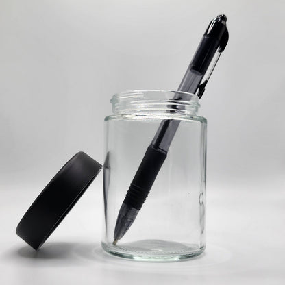Clear glass jar with a black pen inside on a white background