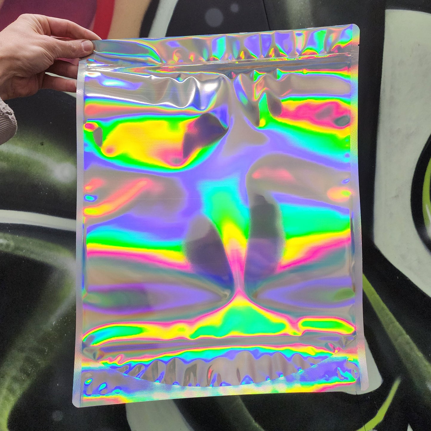 Laser Black size P mylar bag held by a hand with a colorful background