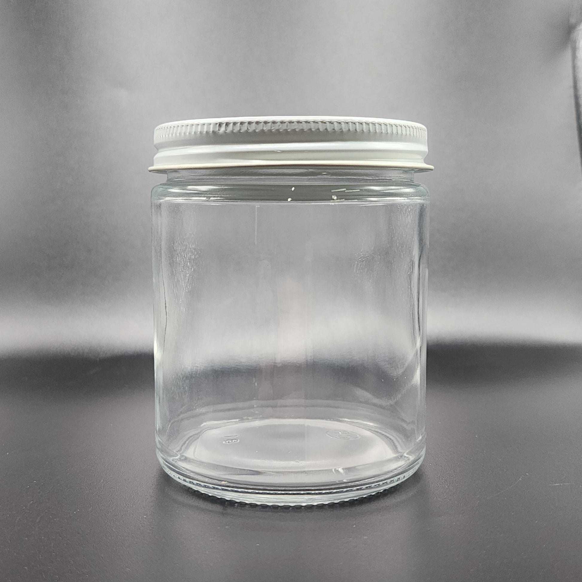 Clear glass jar with a metal lid on a gray background