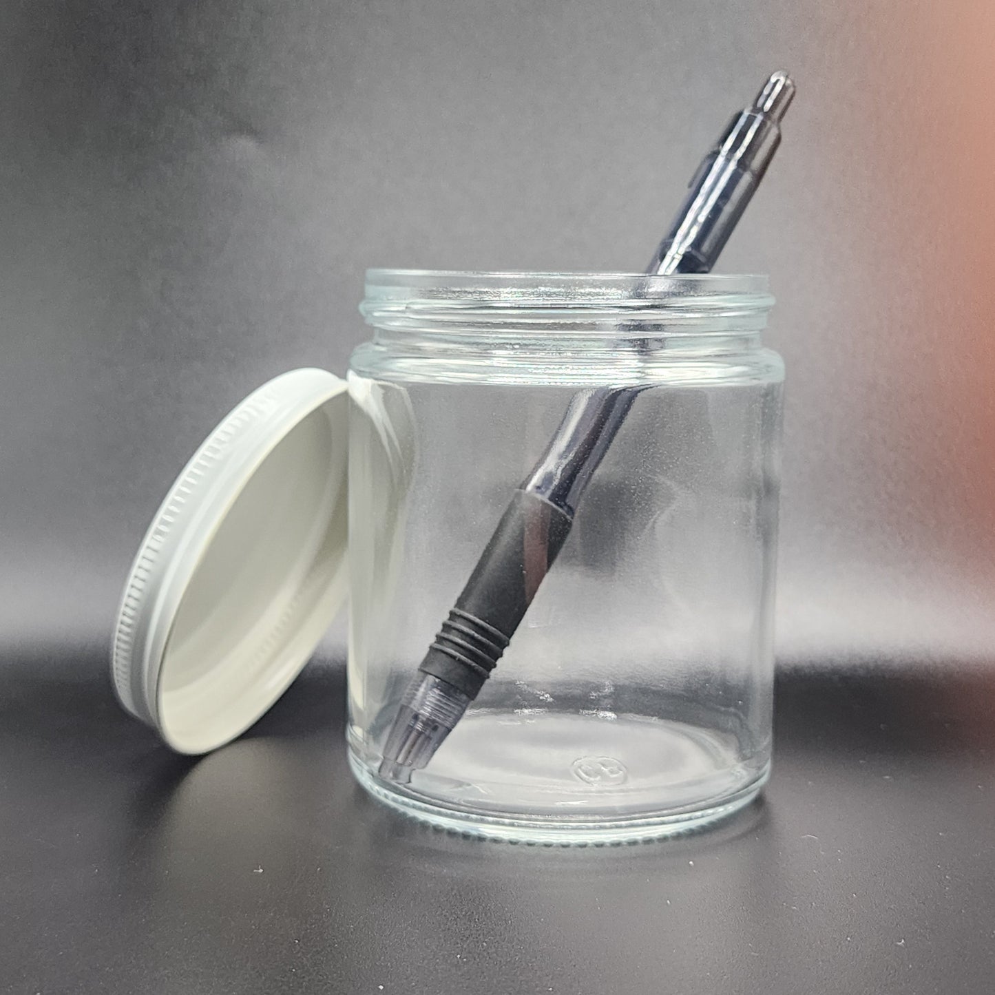 Clear glass jar with black pen and white lid on a gray background