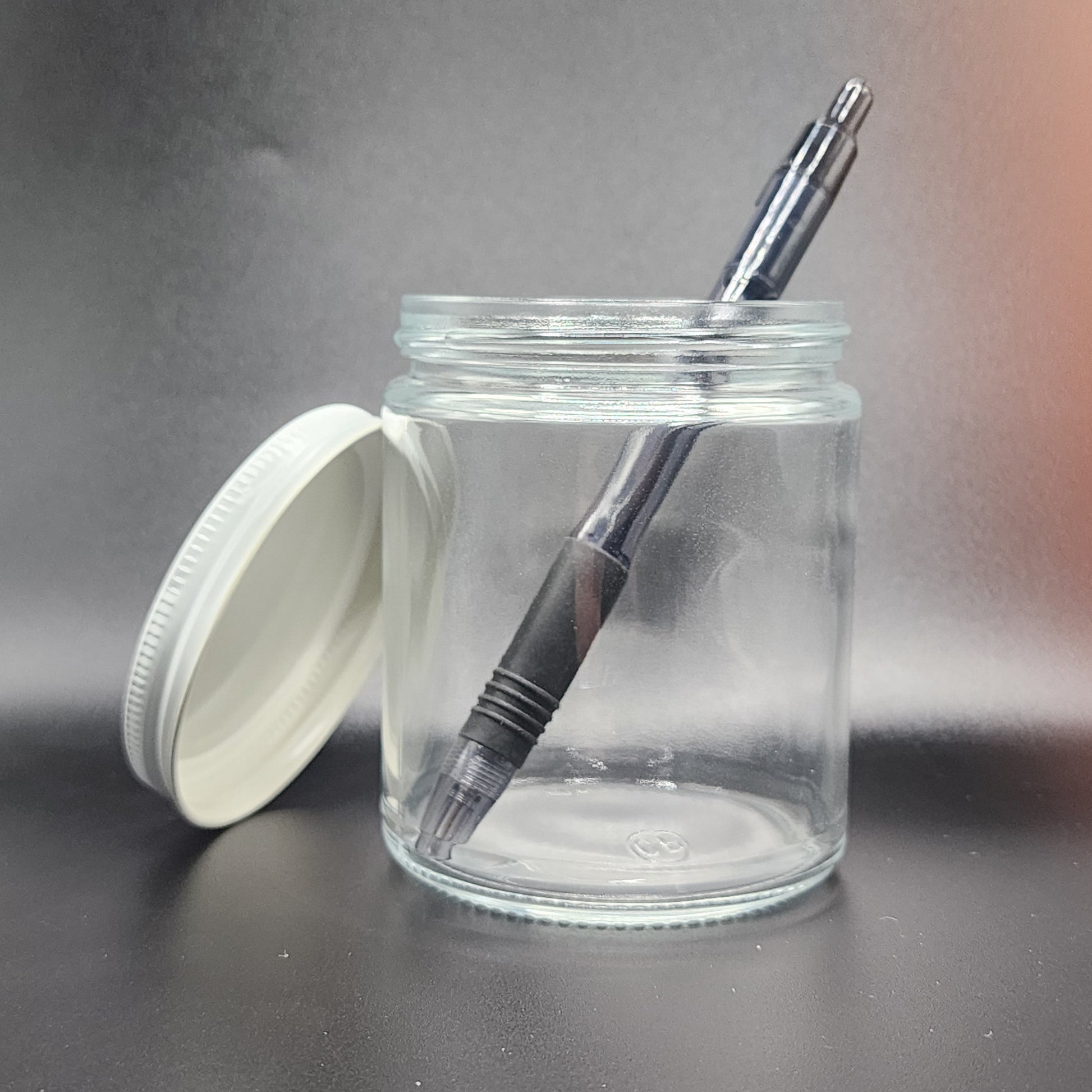 Clear glass jar with black pen and white lid on a gray background