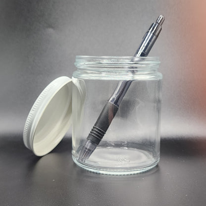 Clear glass jar with black pen and white lid on a gray background