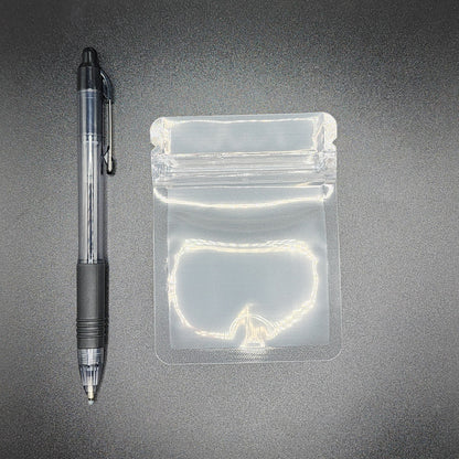 Clear 3x4 mylar bag next to a black pen on a black background
