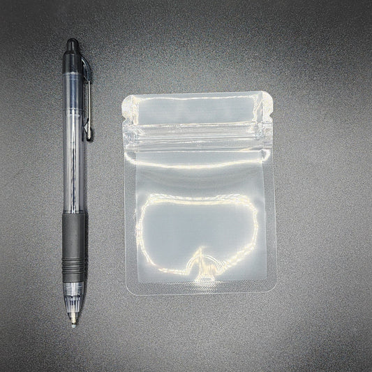 Clear 3x4 mylar bag next to a black pen on a black background