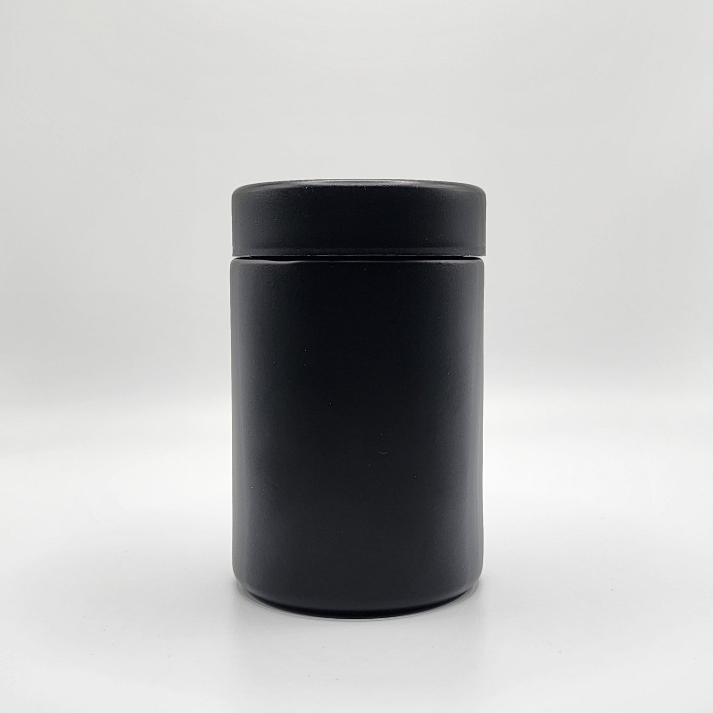 Black cylindrical container with lid on a white background