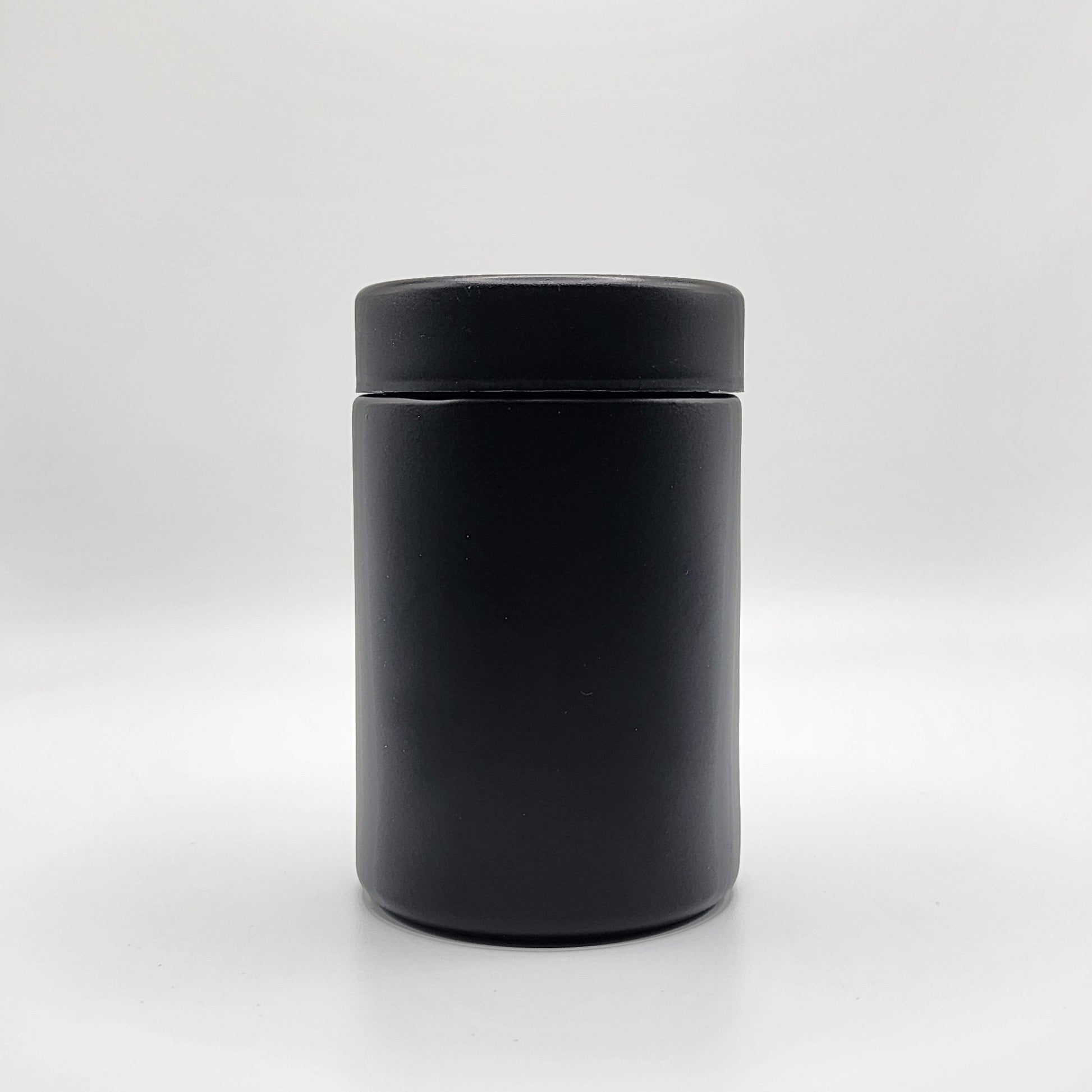 Black cylindrical container with lid on a white background