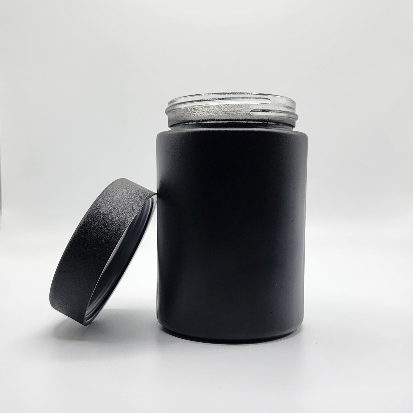 Black cylindrical container with a clear lid on a white background