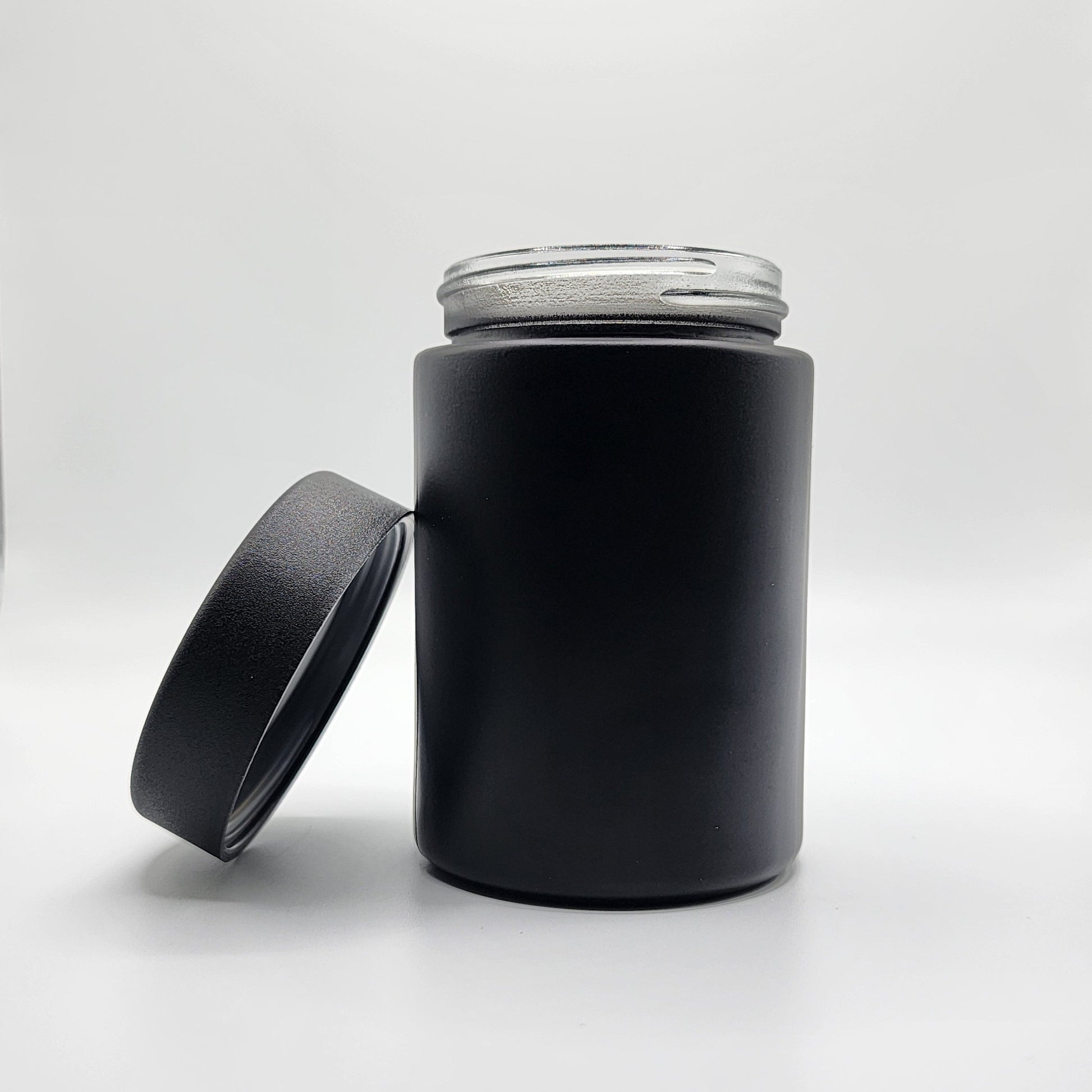 Black cylindrical container with a clear lid on a white background